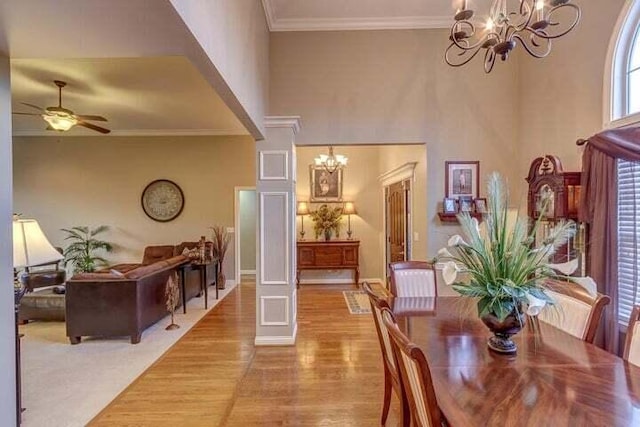 dining space featuring light wood-type flooring, ceiling fan with notable chandelier, and ornamental molding