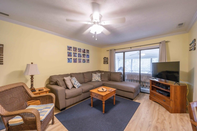 living room with crown molding, ceiling fan, and light wood-type flooring