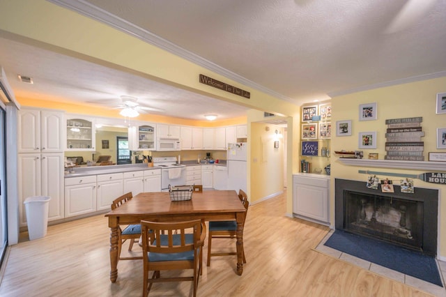 dining space featuring a textured ceiling, ceiling fan, light wood-type flooring, and crown molding