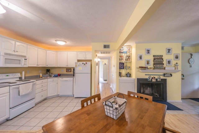 kitchen with light hardwood / wood-style flooring, white appliances, white cabinetry, and a textured ceiling