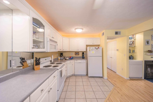 kitchen with light wood-type flooring, white appliances, and white cabinetry