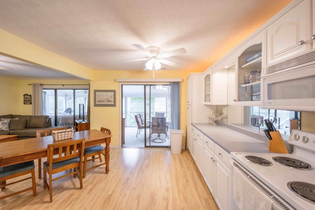 kitchen featuring range, white cabinetry, ceiling fan, light wood-type flooring, and a textured ceiling