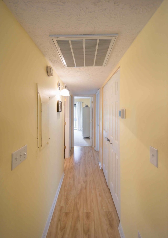 hallway featuring a textured ceiling and light hardwood / wood-style flooring