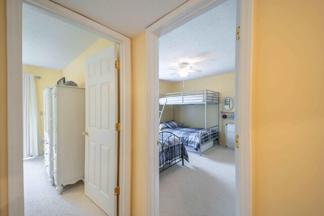 carpeted bedroom with ceiling fan and a textured ceiling