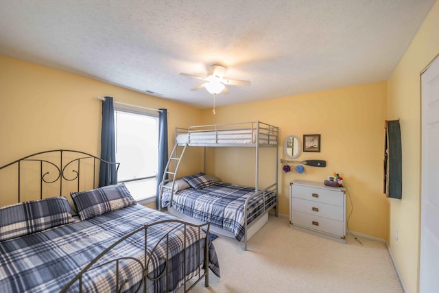 bedroom featuring light carpet, a textured ceiling, and ceiling fan