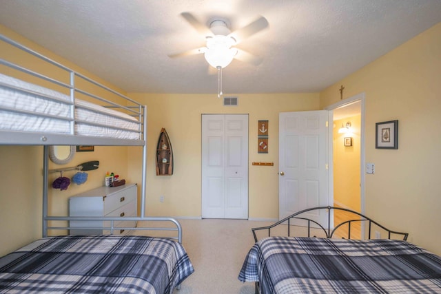 bedroom featuring ceiling fan, a closet, carpet, and a textured ceiling