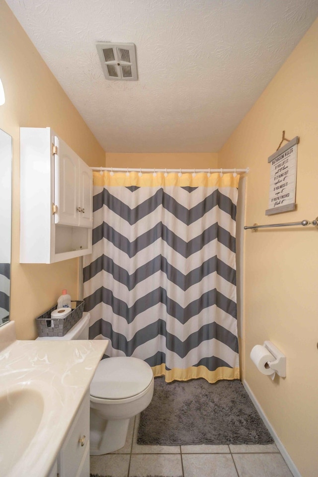 bathroom with a textured ceiling, vanity, toilet, and tile floors