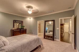 carpeted bedroom featuring ceiling fan and ornamental molding