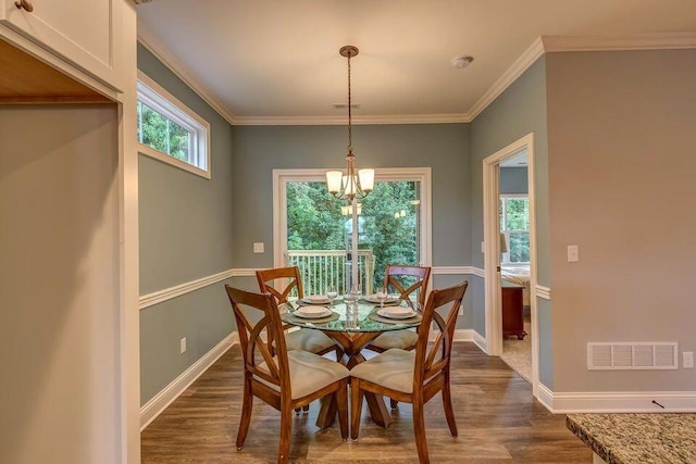 dining area featuring crown molding, dark hardwood / wood-style floors, and an inviting chandelier