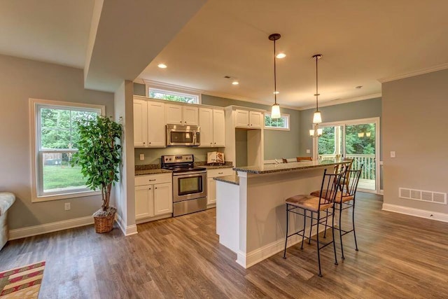 kitchen with baseboards, visible vents, white cabinets, appliances with stainless steel finishes, and wood finished floors