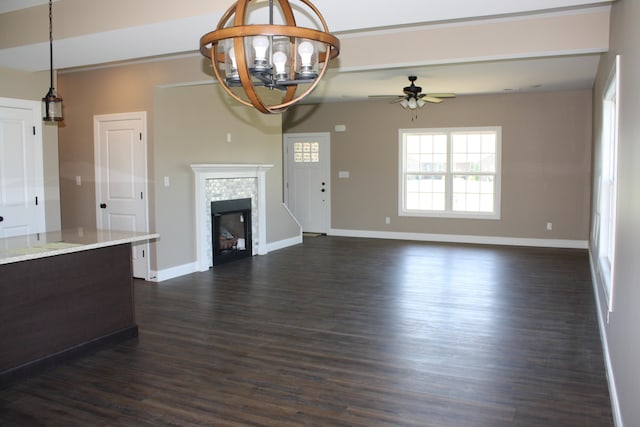 unfurnished living room featuring ceiling fan with notable chandelier, dark hardwood / wood-style floors, and a tile fireplace