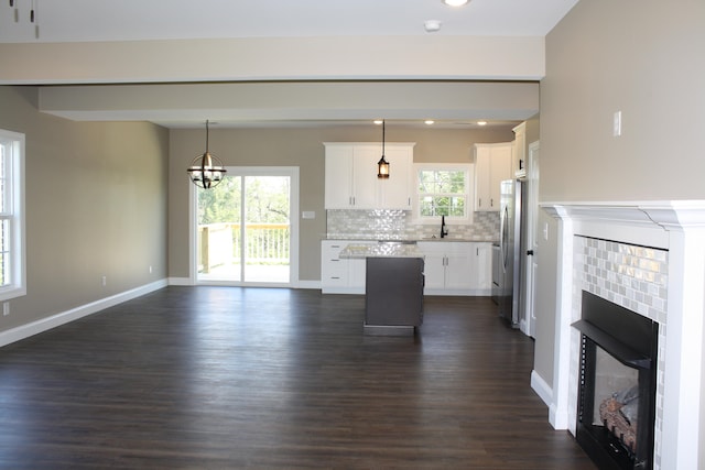 unfurnished living room with a notable chandelier, dark wood-type flooring, a brick fireplace, and sink