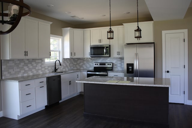 kitchen with dark hardwood / wood-style flooring, appliances with stainless steel finishes, hanging light fixtures, and white cabinetry