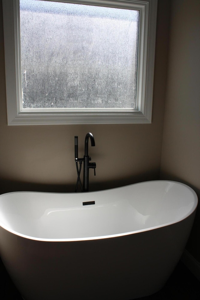 bathroom with a healthy amount of sunlight and a bath to relax in