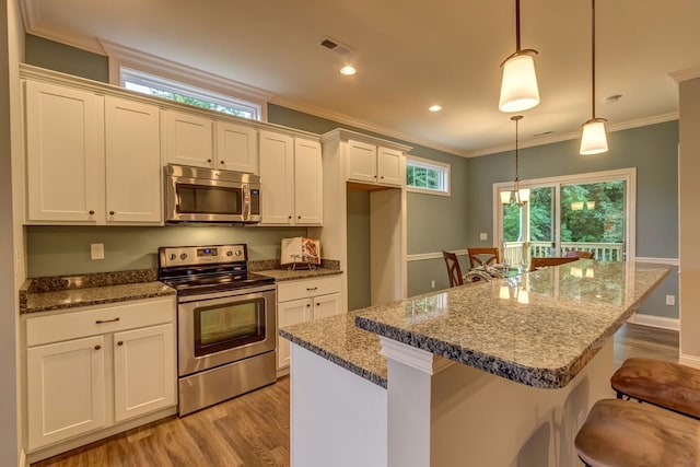 kitchen with light wood-type flooring, a center island, a breakfast bar, stainless steel appliances, and decorative light fixtures