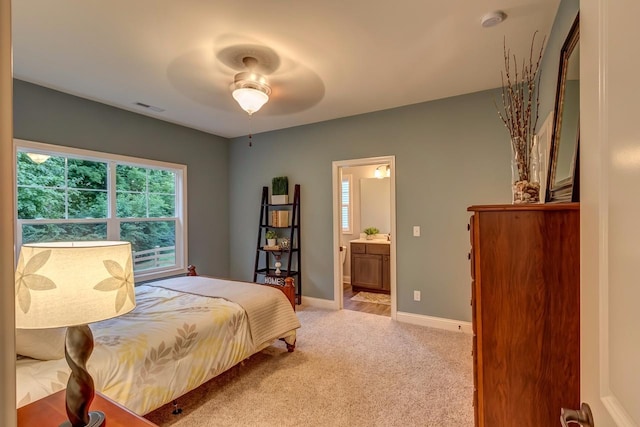 bedroom with light carpet, ensuite bath, and ceiling fan