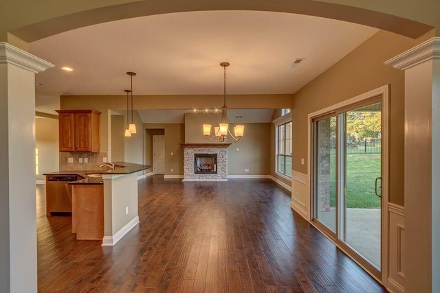 kitchen featuring a fireplace, decorative backsplash, dishwasher, kitchen peninsula, and dark wood-type flooring