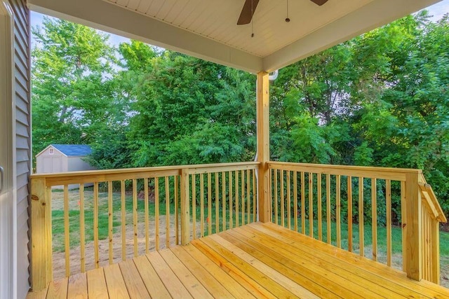 wooden terrace featuring ceiling fan, a yard, and a shed