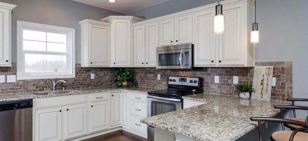 kitchen featuring appliances with stainless steel finishes, light stone countertops, sink, white cabinets, and decorative backsplash