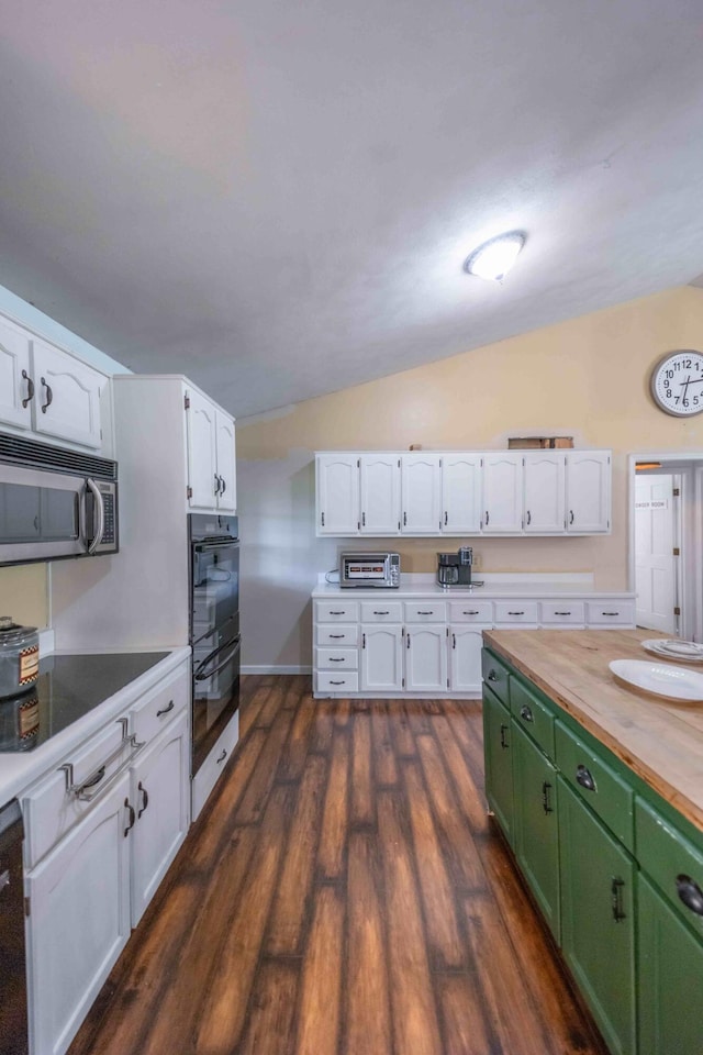 kitchen with dark wood-type flooring, butcher block countertops, stainless steel appliances, vaulted ceiling, and green cabinets