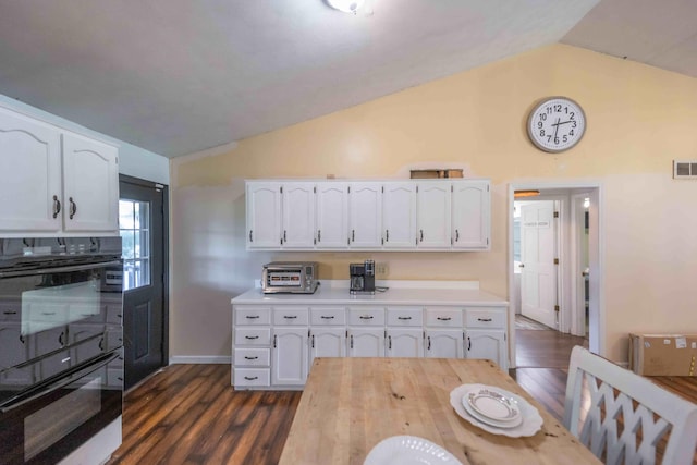 kitchen with double oven, white cabinets, lofted ceiling, and dark hardwood / wood-style floors