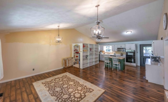 dining area featuring dark hardwood / wood-style flooring, sink, lofted ceiling, and a notable chandelier