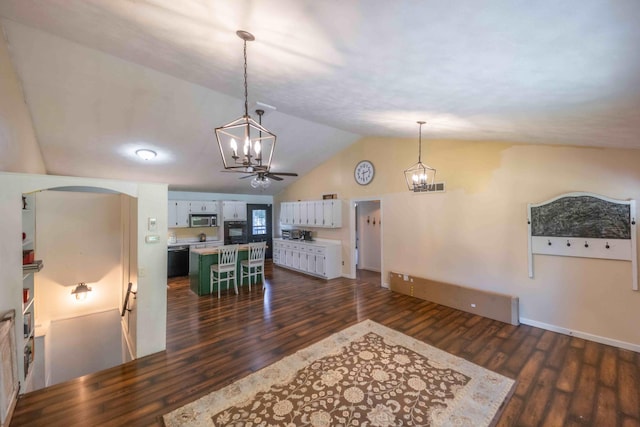 interior space featuring lofted ceiling, ceiling fan with notable chandelier, and dark hardwood / wood-style flooring