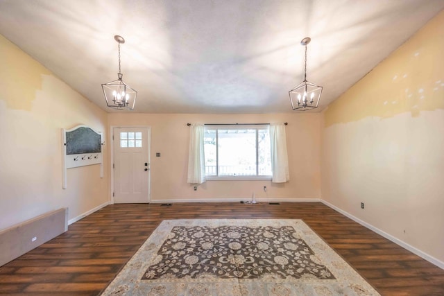 entryway with lofted ceiling, dark wood-type flooring, and a chandelier