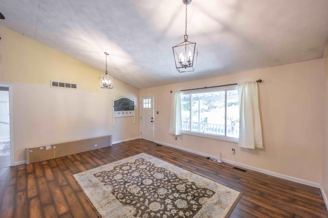 entrance foyer featuring a notable chandelier, dark wood-type flooring, and vaulted ceiling