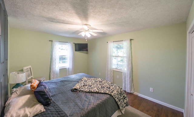 bedroom with dark hardwood / wood-style flooring, ceiling fan, and a textured ceiling