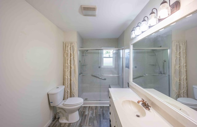 bathroom featuring toilet, large vanity, a shower with shower door, and wood-type flooring