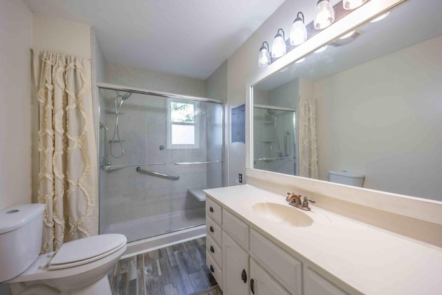 bathroom featuring toilet, hardwood / wood-style floors, an enclosed shower, and vanity