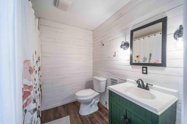 bathroom featuring oversized vanity, hardwood / wood-style floors, toilet, and wood walls