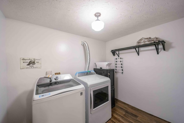 laundry room featuring dark hardwood / wood-style flooring, washer and clothes dryer, and a textured ceiling