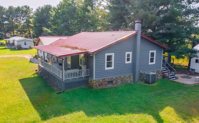 rear view of property with central air condition unit and a yard