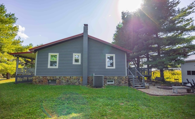 rear view of property with a wooden deck, central AC unit, and a lawn