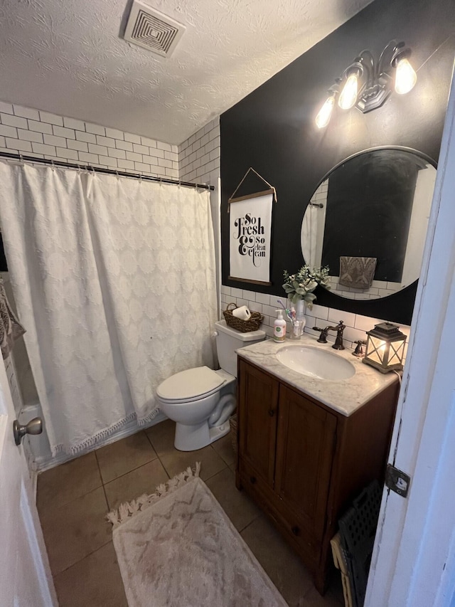 bathroom featuring vanity, toilet, a textured ceiling, a shower with curtain, and tile patterned flooring