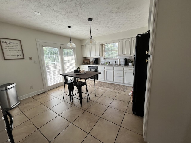 kitchen with white cabinets, decorative light fixtures, light tile patterned floors, and black appliances