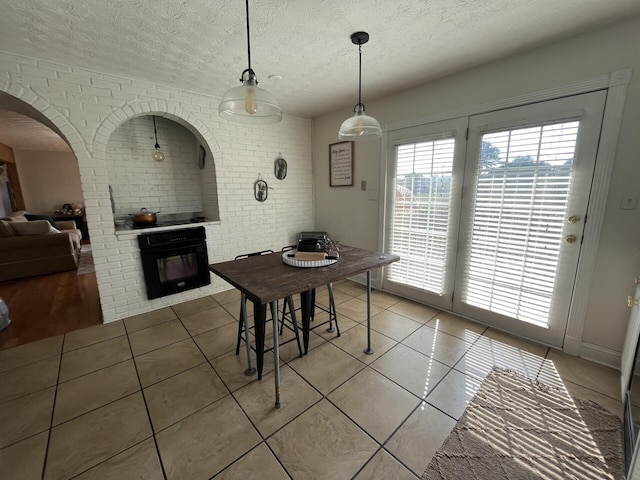 dining area featuring tile patterned flooring, brick wall, and a textured ceiling