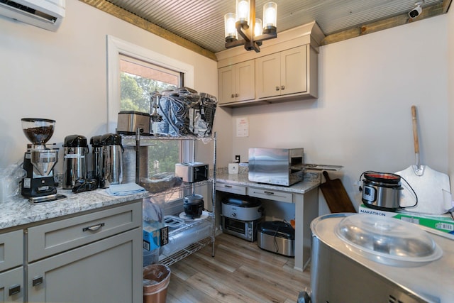 kitchen featuring decorative light fixtures, light hardwood / wood-style flooring, gray cabinets, a wall mounted AC, and a notable chandelier