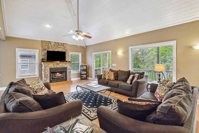 living room with ceiling fan, a stone fireplace, light hardwood / wood-style floors, lofted ceiling, and wood ceiling