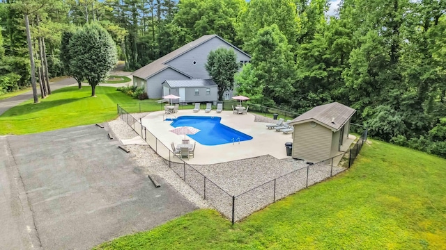 view of pool featuring a lawn, an outdoor structure, and a patio