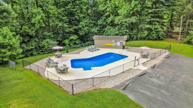 view of swimming pool featuring a lawn, a patio area, and an outbuilding