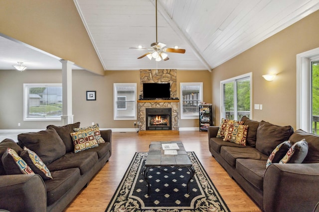 living room featuring vaulted ceiling with beams, decorative columns, a fireplace, and light hardwood / wood-style flooring