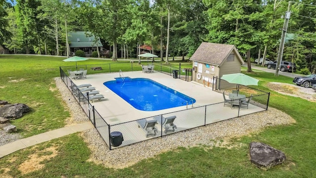 view of swimming pool with an outbuilding, a yard, and a patio