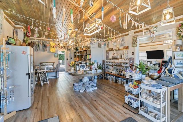 interior space with a high ceiling, white fridge, hardwood / wood-style flooring, and wooden ceiling