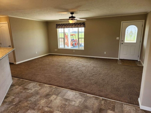 interior space featuring ceiling fan, ornamental molding, dark colored carpet, and a textured ceiling