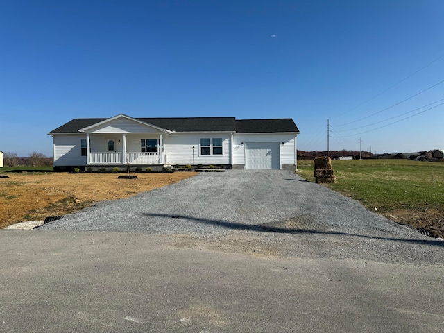 ranch-style house featuring covered porch, a front yard, and a garage