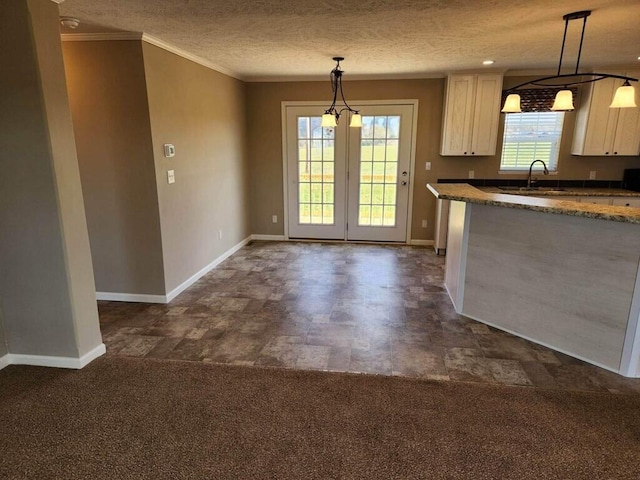 kitchen featuring hanging light fixtures, sink, dark carpet, crown molding, and french doors