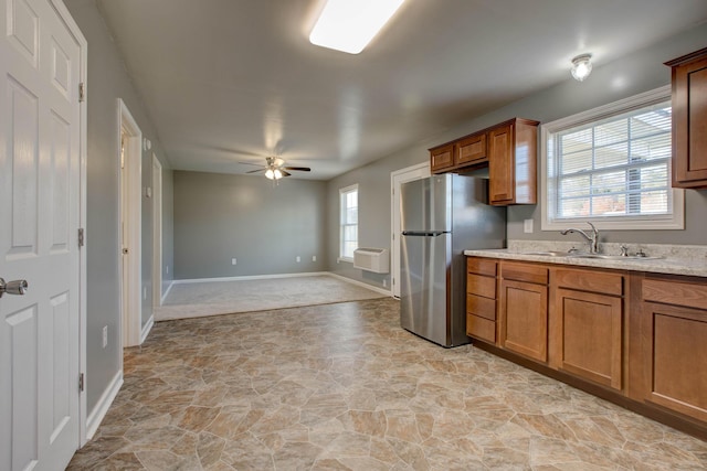 kitchen with light tile floors, ceiling fan, light stone counters, stainless steel refrigerator, and sink